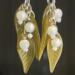 Mistletoe earrings against black backdrop. Silver components with green lucite leaves and white lucite "mistletoe" beads. 
